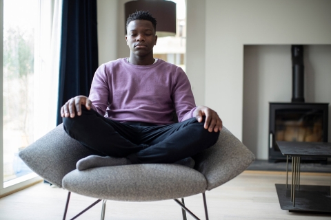 Image of black teen meditating while sitting in a chair